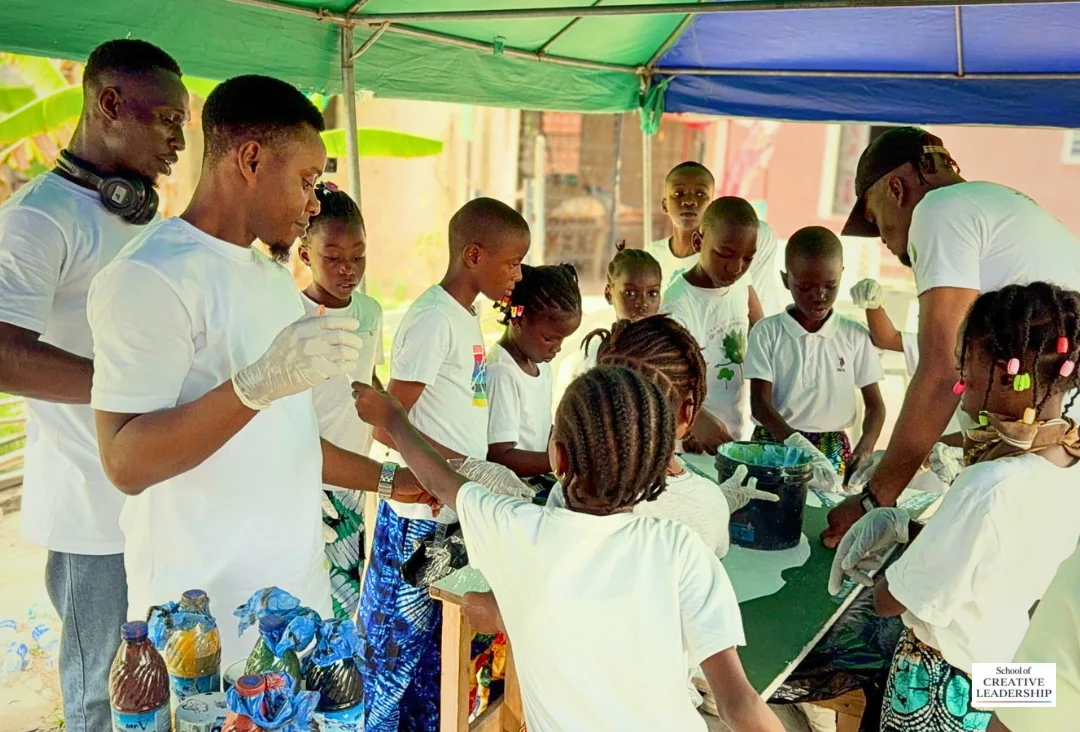 Fellows and children creating a collaborative artwork at the Rebirth Canvas project